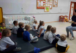 Dzieci siedzą na materacu i słuchają fragmentu książki A.A. Milne Kubuś Puchatek